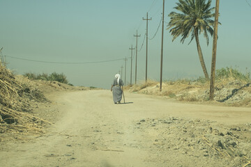 Solitary figure walking on a dusty road