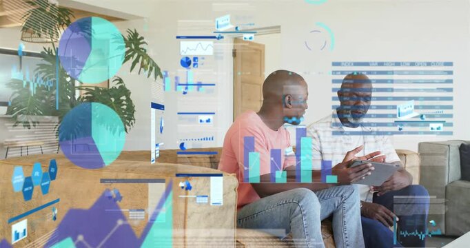 Son leaning while father tapping tablet creating finance charts drifting over them reviewing funds