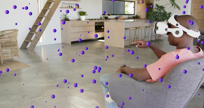 Man wearing VR headset raising right hand, pointing and selecting purple spheres in technology demo