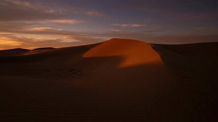 Shadows move across a desert sand dune in a dramatic sunset time-lapse. Vertical video of the golden hour light fading in an arid landscape - Powered by Adobe