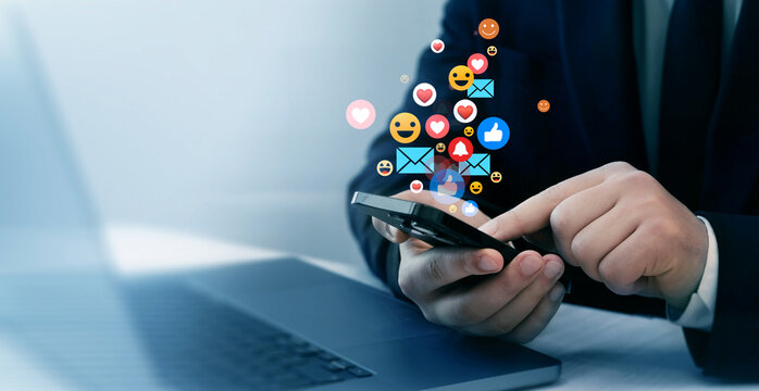 Person using smart phone with emoticon icons of Social Media.Interactive with friends on chat with emoticon feedback.Social media,marketing, like,social network,blog,live,chat reaction and livestream.