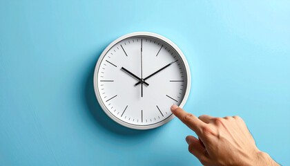Minimalist white clock on light blue wall with hand touching it indicating time passage