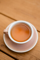 Cup of hot tea on wooden table, minimalistic composition with warm tones. Cozy morning atmosphere, concept of relaxation, mindfulness, and simple lifestyle.