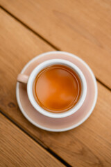 Top view of a cup of hot tea on wooden table, minimalist composition with warm natural tones. Cozy moment, concept of calm morning, relaxation, mindfulness, and slow lifestyle.