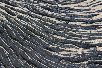 Contrasting Lava and Sand Pattern – Volcanic Coastal Formation with Ribbon-like Basalt Flow and Light Sediment
