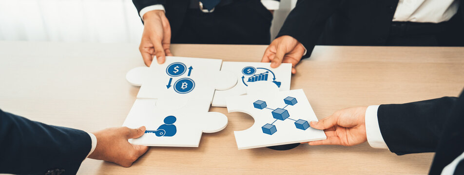 A diverse business team collaborates to fit together puzzle pieces depicting essential concepts like finance and strategy in a modern office setting, symbolizing teamwork and success. Amity - Powered by Adobe