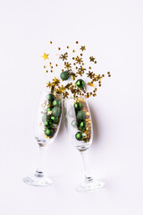 Bright festive composition with champagne glasses with shining Christmas and New Year decorations on white background top view Christmas and New Year party concept