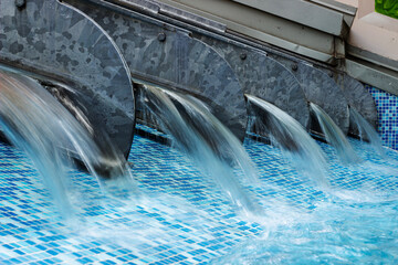 Modern water cascade in blue tiled pool