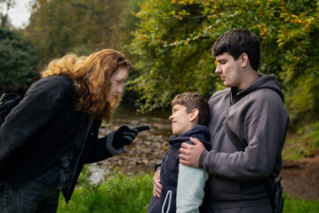 A mother speaks sternly to her sons, a young boy and a young guy, who are lost in strange city and the woman is very scared for them. Communication between mother and sons