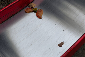 The shiny metal surface of a children's slide in autumn