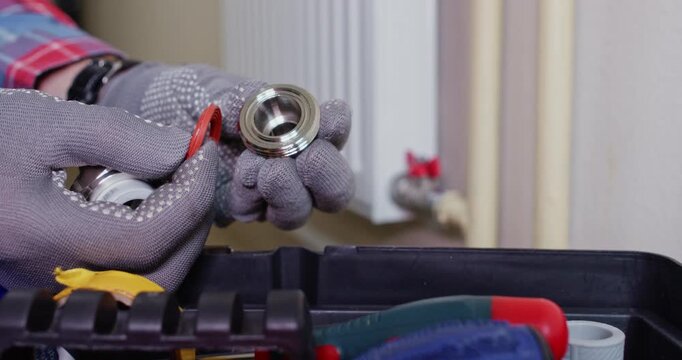 Installer disassembles union inspecting fiber gasket with ferrule. Professional worker verifies thread pitch while comparing part code to reference sheet near toolbox