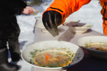 A chef decorates a hot bowl of crayfish soup, steam rising from the plate