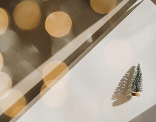 Minimalistyczne świąteczne tło z małą choinką i złotym bokeh w ciepłym naturalnym świetle, elegancki design z miejscem na tekst © Kacper