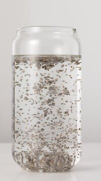 Stirring chia seeds in a glass of water on a white background, side view, macro