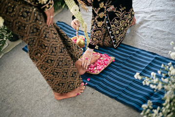 Traditional Batik Wedding Ceremony With Petals, Ornate Dress, and Blue Mat Setting