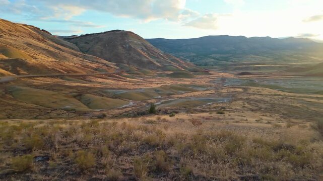 Vivid panoramic view of Painted Hills' vibrant red, gold, black layers from an elevated viewpoint at John Day Fossil Beds National Monument at sunrise