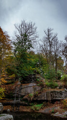 Thin waterfalls over granite terraces beneath autumn trees and sky 