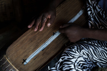 Hand of man closeup playing a stringed instrument in tourist cultural Village experience