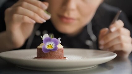 Culinary professional carefully garnishing small dessert with edible flower
