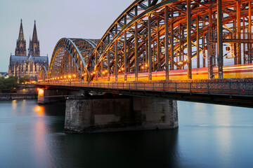 Historic Hohenzollern Bridge Long Exposure. A train streaks over the Hohenzollern bridge over the Rhine river with the Cologne Cathedral rising in the background. Germany.
