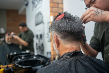 Close-up of barber cutting male client’s hair in small business barbershop interior