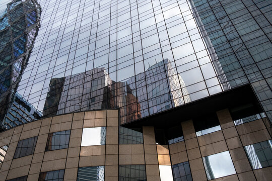 Architectural reflection on modern glass facade of corporate building showcasing symmetry, geometric design and structure within a clean urban context