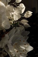 Elegant white Christmas flowers decorated with golden elements on a dark background. The flowers are softly illuminated, creating a festive and luxurious holiday mood