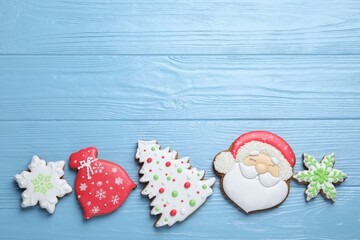 Tasty gingerbread cookies on light blue wooden background, flat lay with space for text. Christmas...