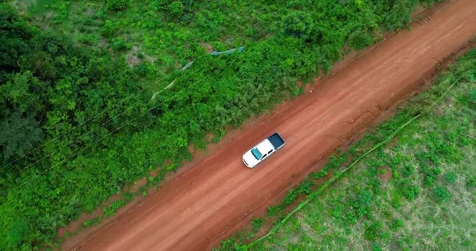 Aerial view of a white vehicle moving on a dusty road