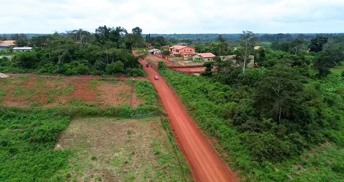 aerial view of dirt road to a town in a forest