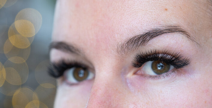 A woman has long extended eyelashes in a close-up with rhinestones. Preparing the image for the holiday