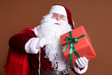 Santa Claus with red bag and Christmas gift on brown background