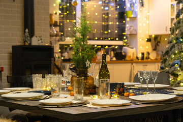 Festive interior of house is decorated for Christmas and New Year in loft style with black stove, fireplace, Christmas tree. Warm studio room with set table, burning wood, cozy and heating of home