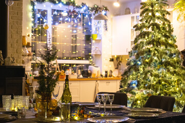 A festive table set for guests for Christmas and New Year, a Christmas tree in the living room, plates, bottles, glasses, potted plants, fairy lights