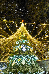 High city Christmas tree with a mushroom cap made of garlands, glows at night on the street. Christmas, New Year, decoration of the city. 