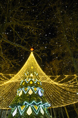 High city Christmas tree with a mushroom cap made of garlands, glows at night on the street. Christmas, New Year, decoration of the city. 