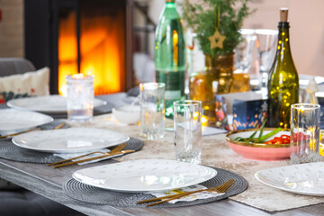 Festive interior of house is decorated for Christmas and New Year in loft style with black stove, fireplace, Christmas tree. Warm studio room with set table, burning wood, cozy and heating of home