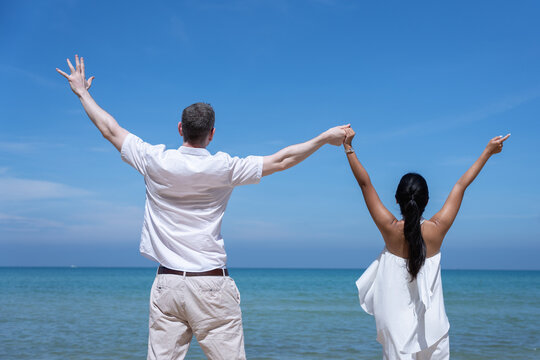 Happy couple jumping together on a tropical beach under a bright blue sky, symbolizing freedom, joy, and love. Perfect for travel, vacation, honeymoon, lifestyle, and summer inspiration concepts. - Powered by Adobe