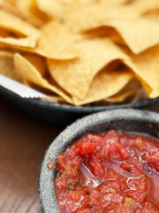Fresh tortilla chips served with spicy salsa in a traditional bowl at a lively restaurant