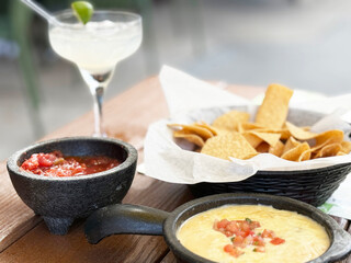 Delicious nachos with cheese dip and salsa paired with a refreshing cocktail on a sunny day