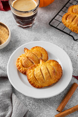 Pumpkin mini pies or hand pies with glass of coffee on a stone background. Traditional autumn dessert for Halloween and Thanksgiving. Copy space