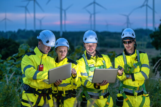 Engineers Team Meeting Night Working Laptop Data Analysis Wind Farm. Digital Monitoring Twilight Renewable Power Site. Night Inspection Using Technology Device