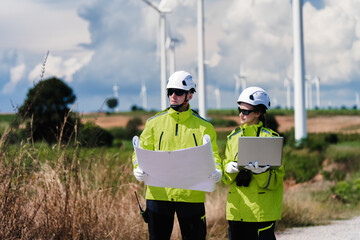 Fototapeta premium Engineers Planning with Blueprint and Digital Technology at Wind Turbine Site. Clean Energy Professionals Analyzing Site Plan Documentation. Collaboration Documentation Wind Power Design.
