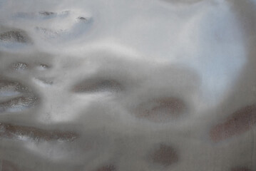 Abstract metallic background texture with a smooth, fluid, liquid-like gradient transitioning into a rougher, textured surface. Futuristic, high-tech, silver, and blue industrial design.