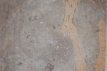 Close-up of unpolished, natural stone or marble texture in gray and taupe with prominent rusty brown vertical veins. Earthy, geological background for architecture or interior design.