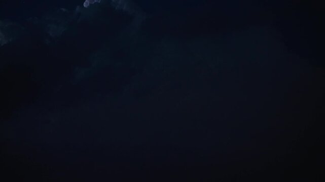 Atmospheric night storm flashing with energy across deep overcast landscape 
