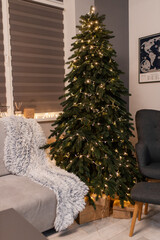 home christmas decor. living room interior for new years celebration. festive wreath, christmas tree. white sheets. couch, blanket, garland, presents. grey. minimalistic