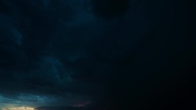 Storm approaching across plain with distant lightning under a moody sky 