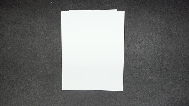 Person holding white empty paper A4 on gray background