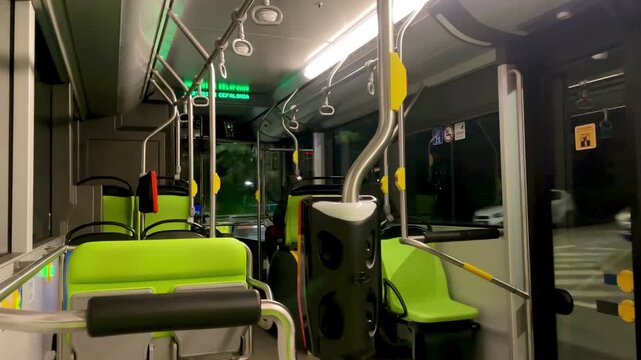 A modern Electric bus interior with rows of green seats, designed for comfortable travel, invites the viewer into its spacious and clean design
